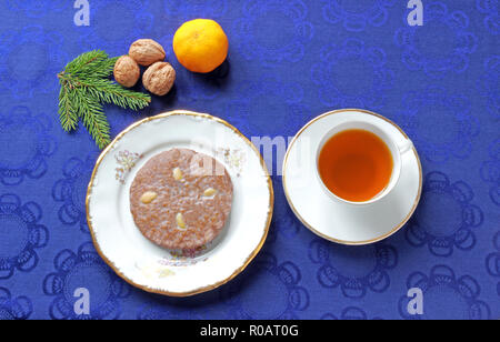 Si tratta di tea time: Tedesco gingerbread cookie, tè, noci e un mandarino su una tovaglia blu Foto Stock