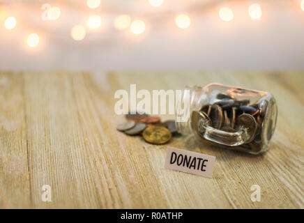 Donare denaro jar risparmi concetto motivazionale sul pannello di legno Foto Stock