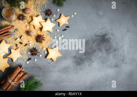 Gastronomia natalizia sfondo con spezie, gingerbread cookies e cottura Ingredienti sul cemento grigio, copia dello spazio. Ingredienti per biscotti di Natale. Foto Stock