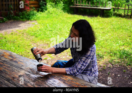 Donna in viaggio da bevande thermos PAC all'esterno. La ragazza si appoggia dopo escursione. Foto Stock