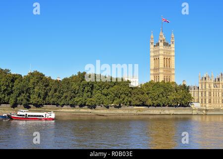 Londra, Inghilterra, Regno Unito. Victoria Tower, con l'Unione Jack battenti dal suo tetto e le case del Parlamento al di là del fiume Tamigi. Foto Stock