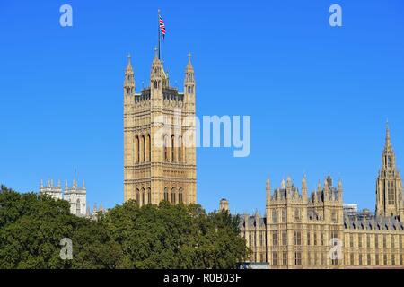 Londra, Inghilterra, Regno Unito. Victoria Tower, con l'Unione Jack battenti dal suo tetto e le case del Parlamento al di là del fiume Tamigi. Foto Stock