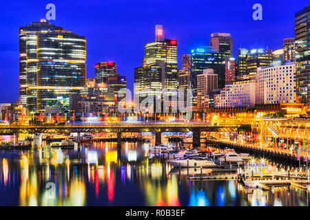 Lungomare della città di Sydney CBD alti torri intorno a Darling Harbour con marina imbarcazioni sul ponte Pyrmont riflettendo ancora in acque al tramonto. Foto Stock