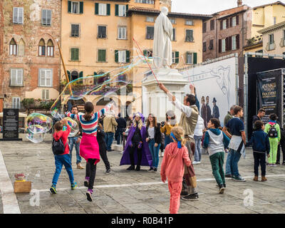 Bambini che giocano con le bolle durante Lucca Comics & Games, annualmente un fumetto e convenzione di gioco nella città murata di Lucca, Toscana, Italia Foto Stock