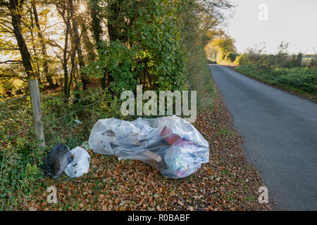 Volare con punta di plastica e cartone Rifiuti su una strada di campagna in Cotswolds. Le stragi, Cotswolds, Gloucestershire, Inghilterra Foto Stock