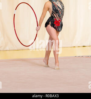 Giovane ginnasta con il cerchio rosso ritratto artistico .flessibilità in acrobazie e fitness salute. Foto Stock