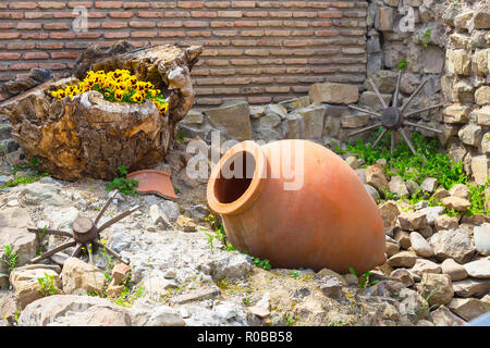 Vecchio stile georgiano tradizionale vino simbolo di regione di sfondo con qvevri caraffa, fiori e legno ruota carrello Foto Stock