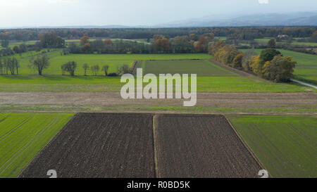 Vista aerea della campagna della Slovenia orientale con campi, boschi e siepi, siepi che dividono campi e prati, Pohorje montagna in fondo Foto Stock