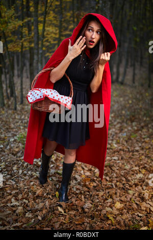 Donna vestita come Cappuccetto Rosso in diverse posture nella foresta Foto Stock