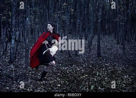 Donna vestita come Cappuccetto rosso acceso di notte attraverso la foresta Foto Stock