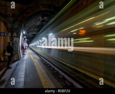 Ad alta velocità treno notte passando attraverso una stazione ferroviaria Foto Stock