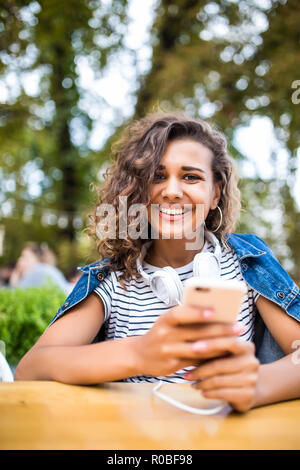 Bella ragazza latina di successo freelancer scrive un messaggio di testo sul telefono mentre è seduto nella caffetteria. Donna attraente la lettura di un messaggio di testo sul Foto Stock