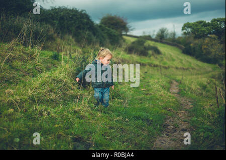 Un piccolo bimbo sta camminando sul pendio di una collina in autunno Foto Stock