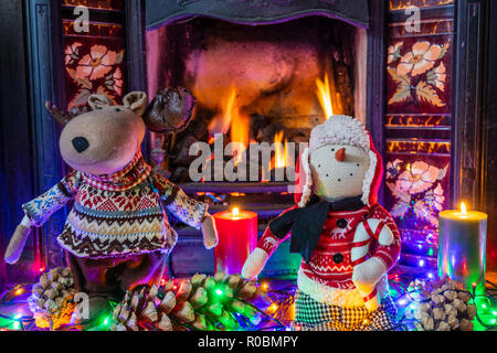 Un pupazzo di neve e renne figurine in piedi vicino al caminetto. Le decorazioni di Natale vacanza permanente figurine Plush Doll Home Caminetto interno ripiano Foto Stock