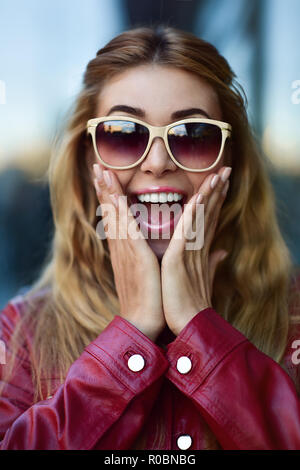 Closeup ritratto della bella pensieroso bionda bianca ragazza caucasica donna, usurata in giacca rossa al di fuori in strada di città, lifestyle ritratto concept Foto Stock