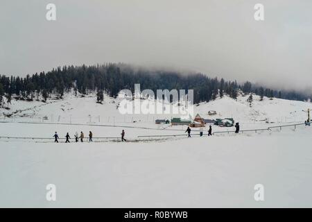 I turisti a piedi lungo una coperta di neve strada durante le stagioni prima nevicata in Gulmarg, a circa 55km da Srinagar, Indiano Kashmir amministrato. Diritto all'avvento dell'inverno, Kashmir valley ha ricevuto la sua prima nevicata come ondata di freddo come le condizioni afferrata la valle a causa di continue acquazzone. Tutte le stazioni meteorologiche attraverso la valle venerdì assistito ad un calo di circa 10 gradi Celsius dalle normali temperature di giorno per questo periodo dell'anno. Foto Stock