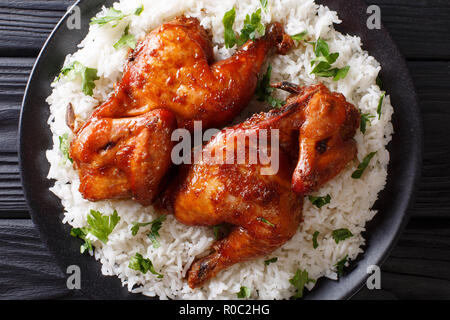 Spicy Mezzo pollo al forno con un sacco di aglio, la salsa di soia, lo zenzero e il miele, servito con riso su una piastra vicino sul tavolo. parte superiore orizzontale vista dal Foto Stock