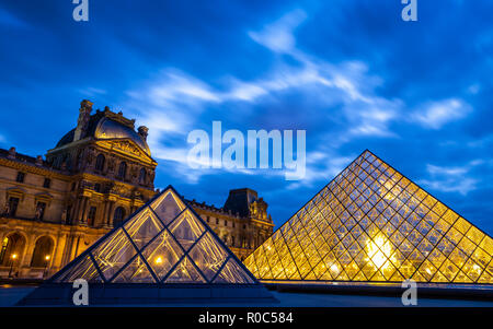 Parigi, Francia - 30 Settembre 2018: Brillante piramidi di vetro all'interno di piazza centrale del museo del Louvre con lunga esposizione della torbida twilight blue sky. Foto Stock