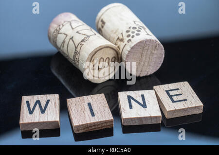 Due tappi accanto a un paio di lettere di legno con la parola vino Foto Stock