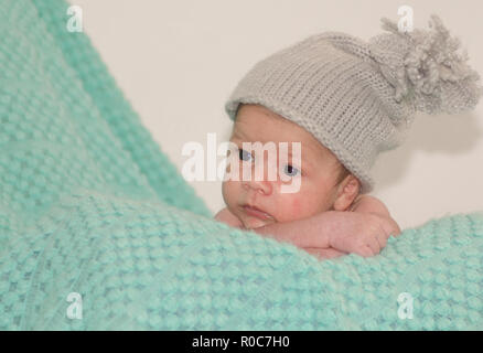 4 settimane di età neonato ragazzo con cappello grigio sulla coperta di verde Foto Stock