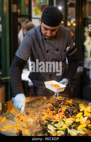 Lo chef serve piatti di pesce Paella in London Borough Market Foto Stock