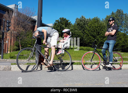 Padre e figlia piccola in sella a una moto e un altro ciclista maschio in attesa al semaforo a Montreal, Quebec, Canada Foto Stock