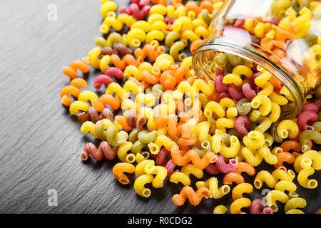 Spirale multicolore pasta sparsi su un nero ardesia sfondo. spazio per il testo Foto Stock