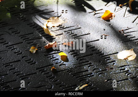 Foglie di autunno su vecchie lapidi con la scrittura Foto Stock