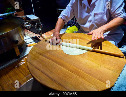 Un cuoco rendendo Gozleme turco, un tradizionale anatolica focacce ripiene, cotto su un fuoco di legno su una piastra. Foto Stock