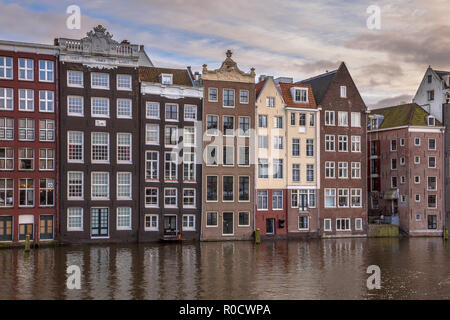 I tradizionali colorati canal case sul lungomare su Damrak nel Patrimonio mondiale dell UNESCO di Amsterdam Foto Stock