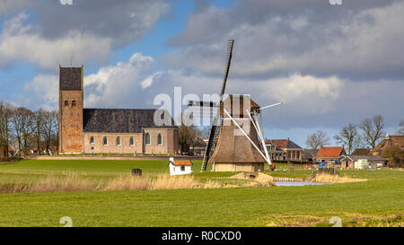 Villaggio di Wanswert con chiesa uno storico Mulino a vento sulla campagna frisone. Appena a nord di Leeuwarden, Frisia Foto Stock