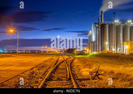 Deviatoio ferroviario in una pesante area industriale con surreale sognanti luci e colori nel crepuscolo Foto Stock