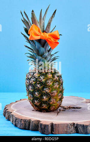 Ananas con capelli arco sulla fetta di legno. Foto Stock