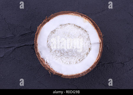 Metà di noce di cocco con scaglie di noce di cocco. Foto Stock