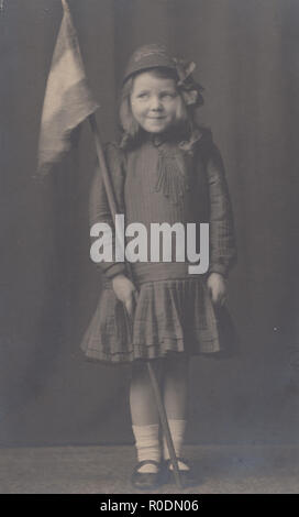 Vintage Cartolina fotografica di una giovane ragazza di nome come Dora Jeanne Schofield tenendo una bandiera Foto Stock