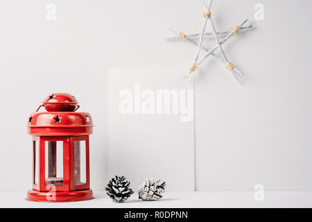 Lanterna rossa con una candela, pigne, star e vuota del foglio bianco su sfondo bianco. Decorazione di natale Foto Stock