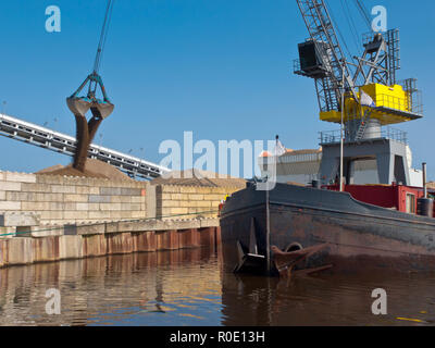 Porto di giallo gru è sabbia di scarico da una nave in un porto olandese Foto Stock