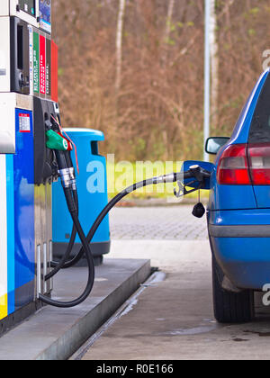 Auto blu alla stazione di gas essendo riempito con carburante contro prezzi gonfiati Foto Stock