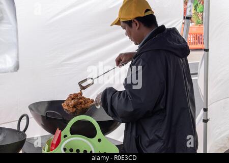 Asain cibo chef di stallo frittura profonda alcuni cibi da strada nel suo wok Foto Stock