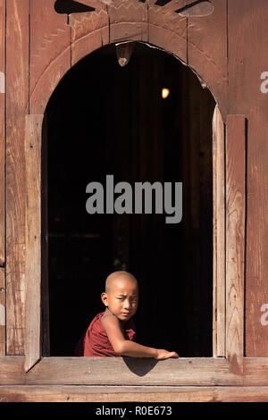 NYAUNG SHWE, Myanmar, 27 gennaio 2015 : un giovane debuttante monaco buddista è guardare la finestra della Shwe Yaunghwe Kyaung monastero a Nyaung Shwe, M Foto Stock