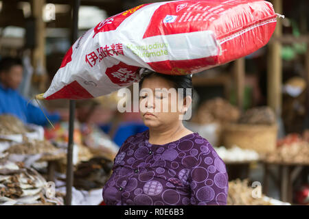 MANDALAY,MYANMAR,17 Gennaio 2015 : Una donna sta portando una grande glutammato monosodico sacco sul suo capo in strada di Mandalay, Myanmar (Birmania). Foto Stock