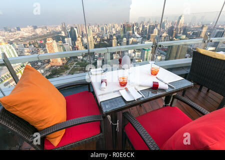 BANGKOK, Thailandia, 14 gennaio 2015: Ristorante tavolo con vista sul paesaggio urbano di cielo rosso del tetto del Centara hotel a Bangkok, in Thailandia. Foto Stock