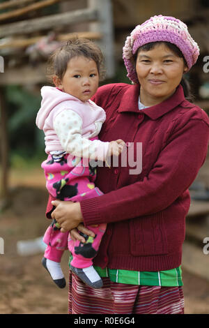 MAE KLANG LUANG, Thailandia, dicembre 31, 2014 : Una tribù Karen donna in abiti tradizionali sta tenendo il suo bambino nel villaggio di Mae Klang Luang nel Foto Stock