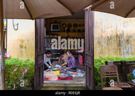 HOI AN, Vietnam, dicembre 14, 2014 : Tre donne sedute sul pavimento sono trinciatura di alcuni vegetali e spezie in casa, Hoi An, Vietnam Foto Stock