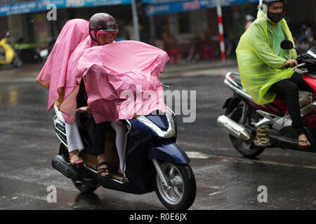 DA NANG, Vietnam, dicembre 14, 2015: popolo vietnamita in sella moto sotto una pioggia pesante, pieno ricoperto con un impermeabile in Da Nang, Vietnam Foto Stock