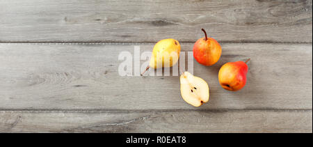 Quattro pere mature, uno tagliato a metà, table top view, ampio formato banner. Foto Stock