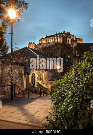 Vista di Edimburgo Il castello, in Scozia, dal Vennel passi al tramonto, con le luci di strada e le luci del castello a. Il viaggio. Paesaggio urbano. Foto Stock