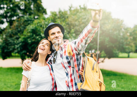 Femmina gioioso e il suo migliore amico avente escursione nel parco, rendendo selfie, avente felici espressioni mentre avvolgente. Maschi e femmine di camminare sulla strada. Foto Stock