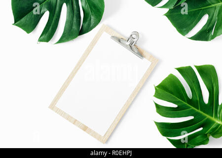 Appunti con foglie di monstera su sfondo bianco laici piana, vista dall'alto Foto Stock