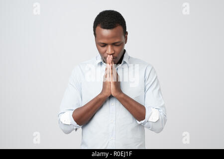 Pregando African American uomo sperare per il meglio. Foto Stock